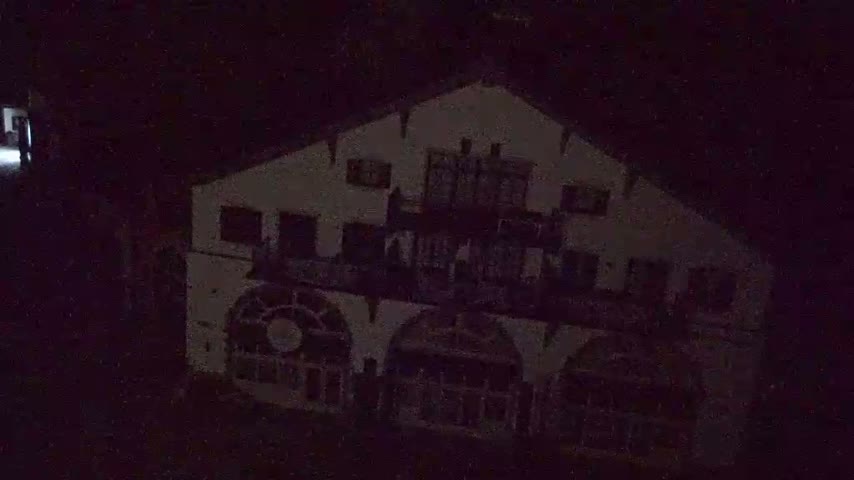 A large, light-colored building with multiple windows and balconies is visible at night.