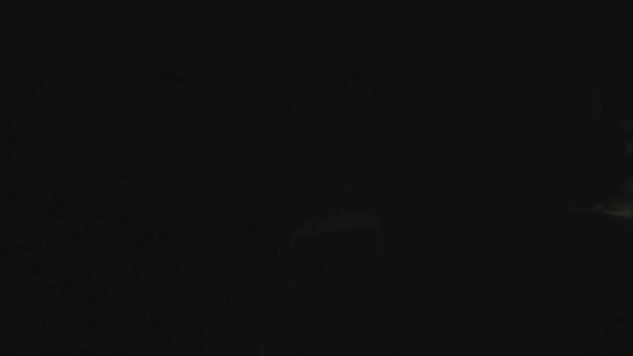 A very dark image shows a hint of light in the bottom right corner, possibly indicating a night scene with a bright area in the distance.