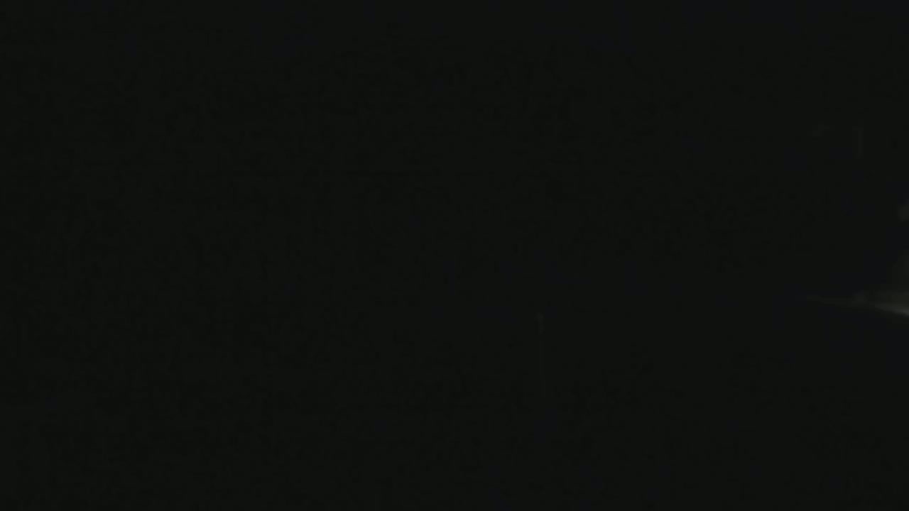 The image is mostly black, with a faint, blurry light source visible in the bottom right corner.