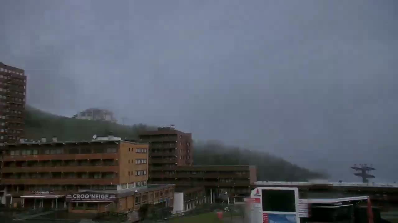 A foggy day reveals several multi-story buildings and a chairlift in a mountainous area.