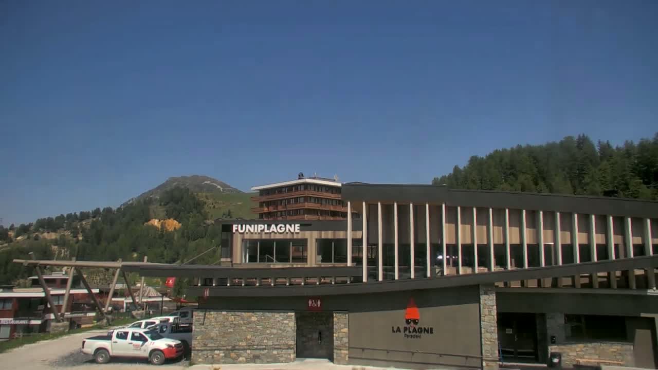A modern building with a mountain backdrop under clear blue skies.