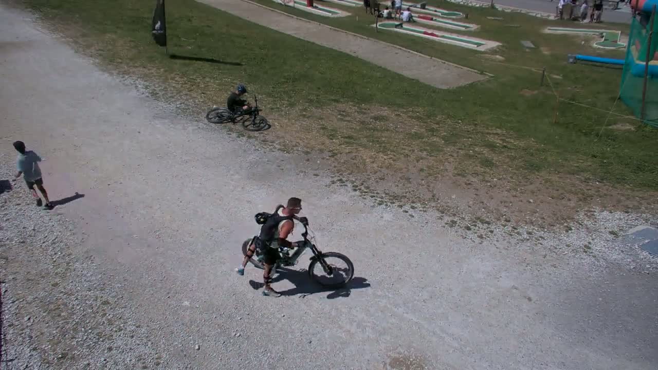 Several people with mountain bikes stand near a chairlift on a sunny day.