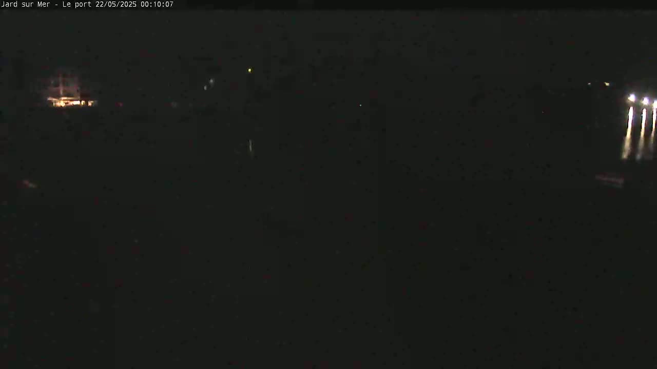 A nighttime, dark image shows a few faint lights in the distance.