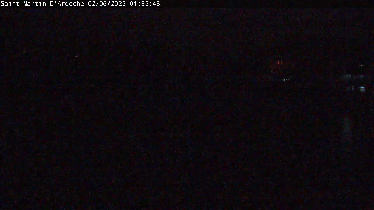 A dark, nighttime scene shows a few faint lights in the distance.