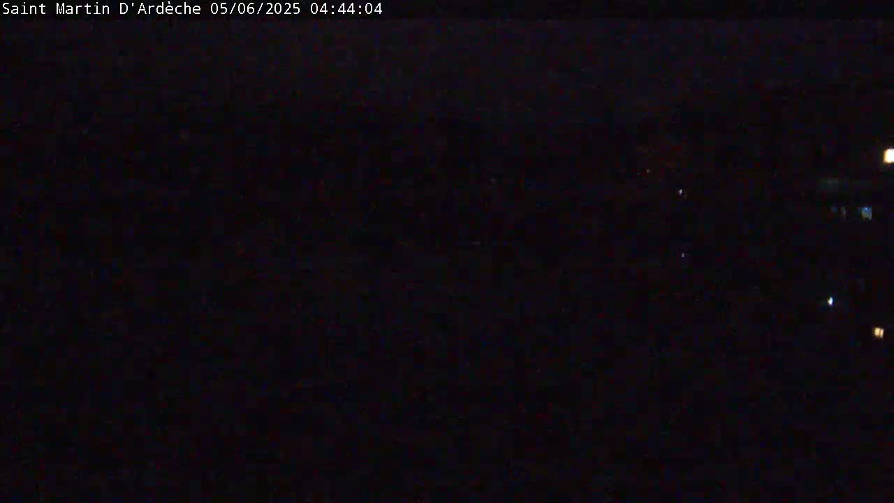 A dark, nighttime scene is visible with a few faint lights in the distance.