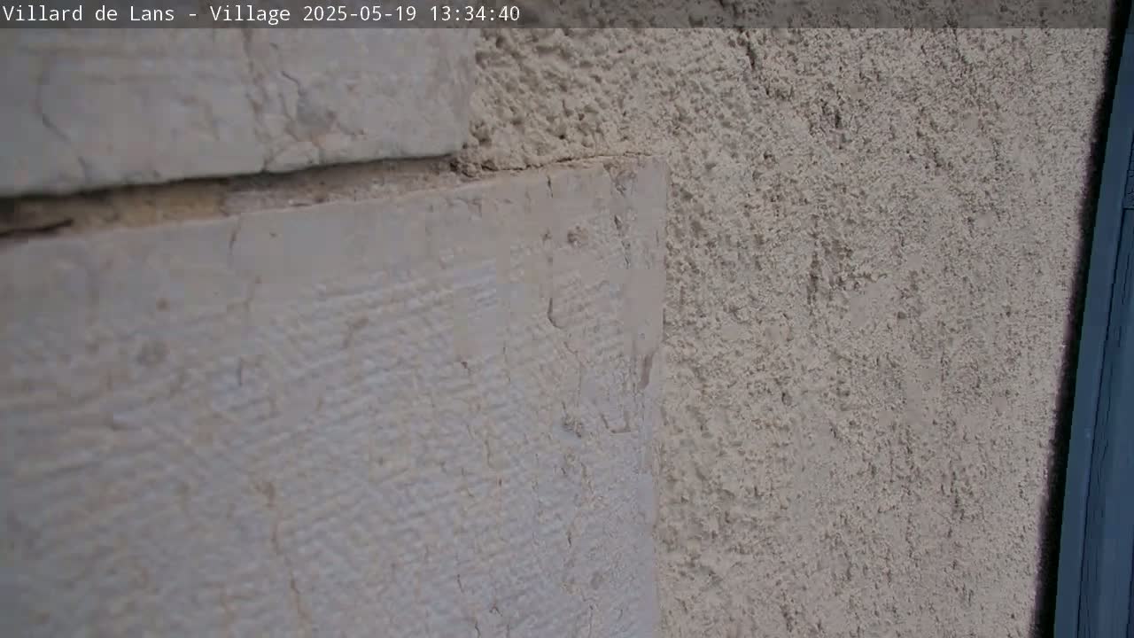 A close-up view shows a section of light beige wall, part of which is smooth stone and part textured stucco.