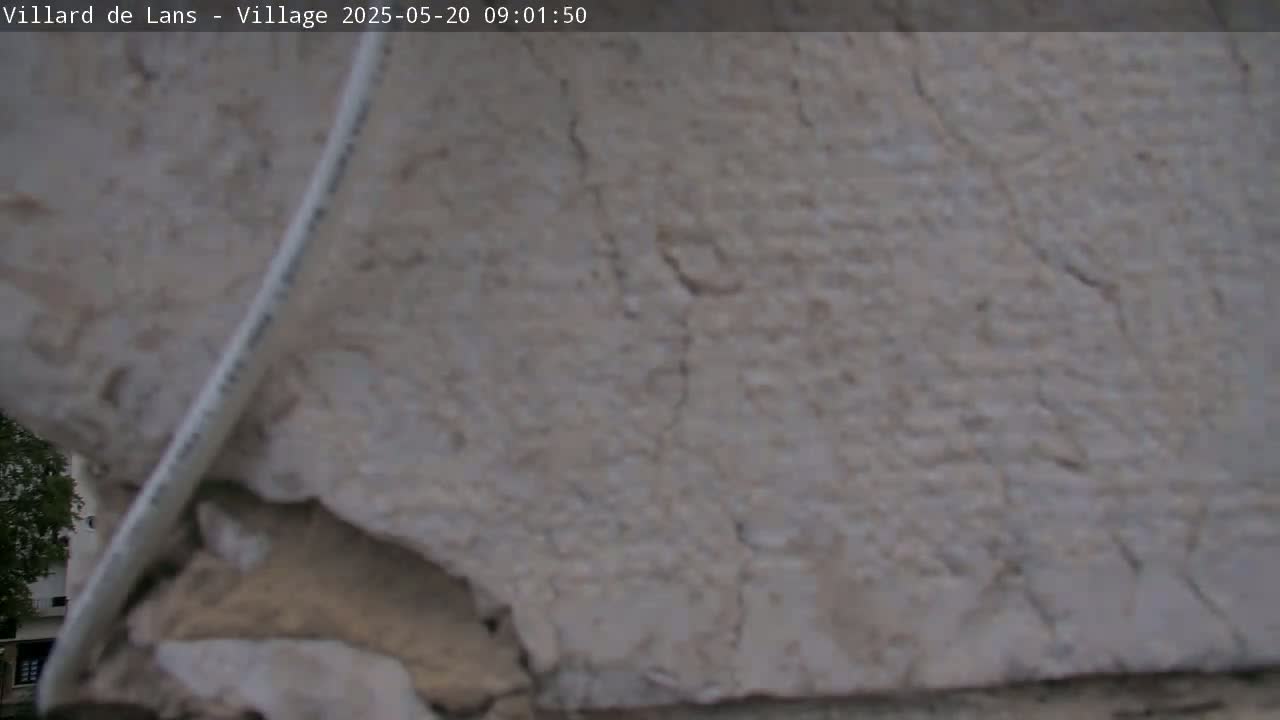 A close-up view shows a light-gray, textured stone surface with cracks, partially obscured by a white cable.