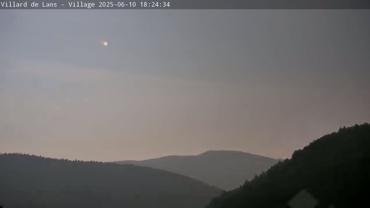 A hazy, dusky sky hangs over a range of dark, silhouetted mountains.