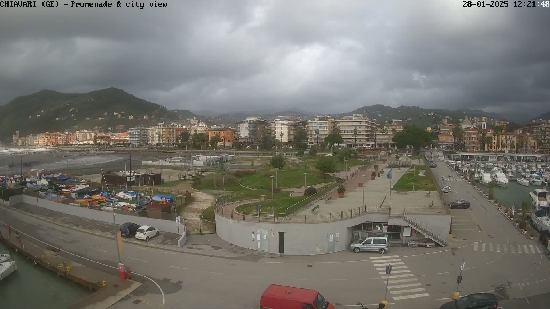 A coastal city with a marina, park, and apartment buildings is viewed under an overcast sky.