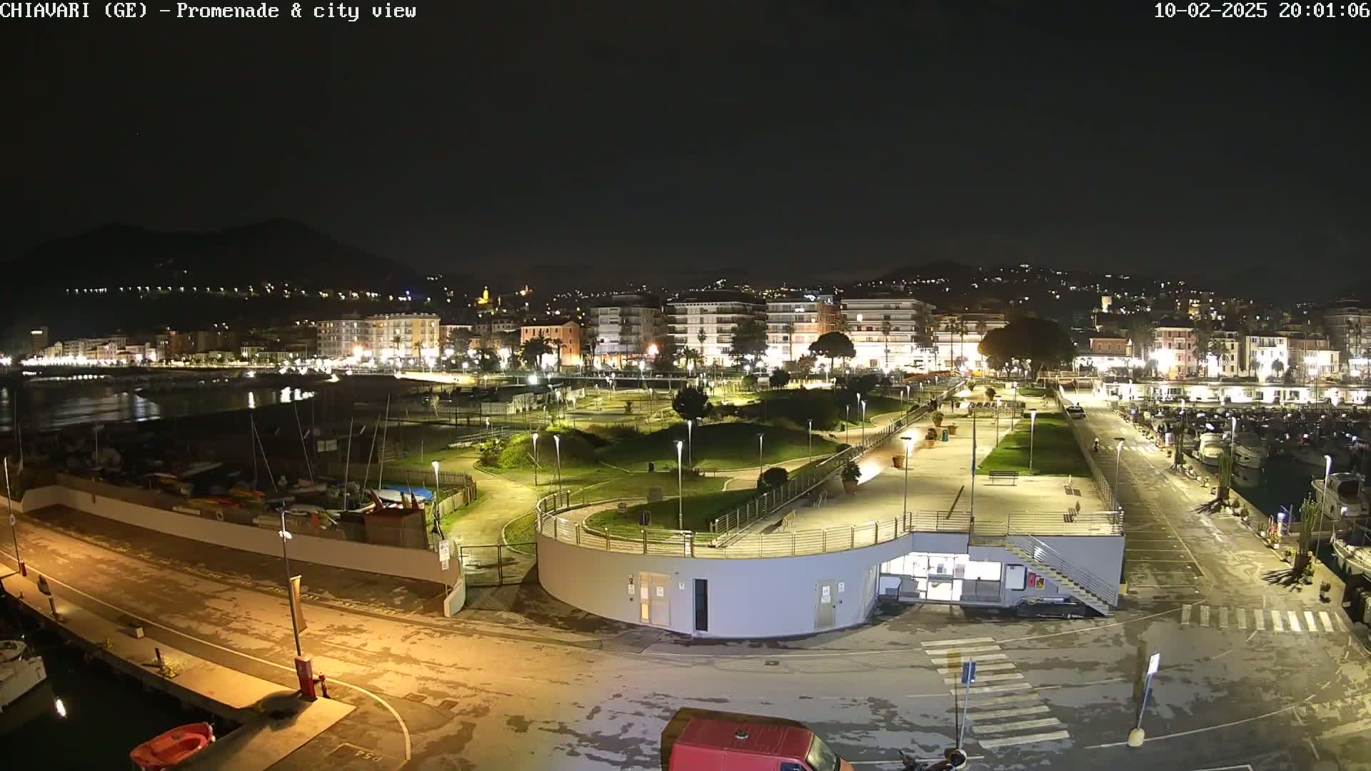 A nighttime view of a harbor with a city lit up in the background, under a clear sky.