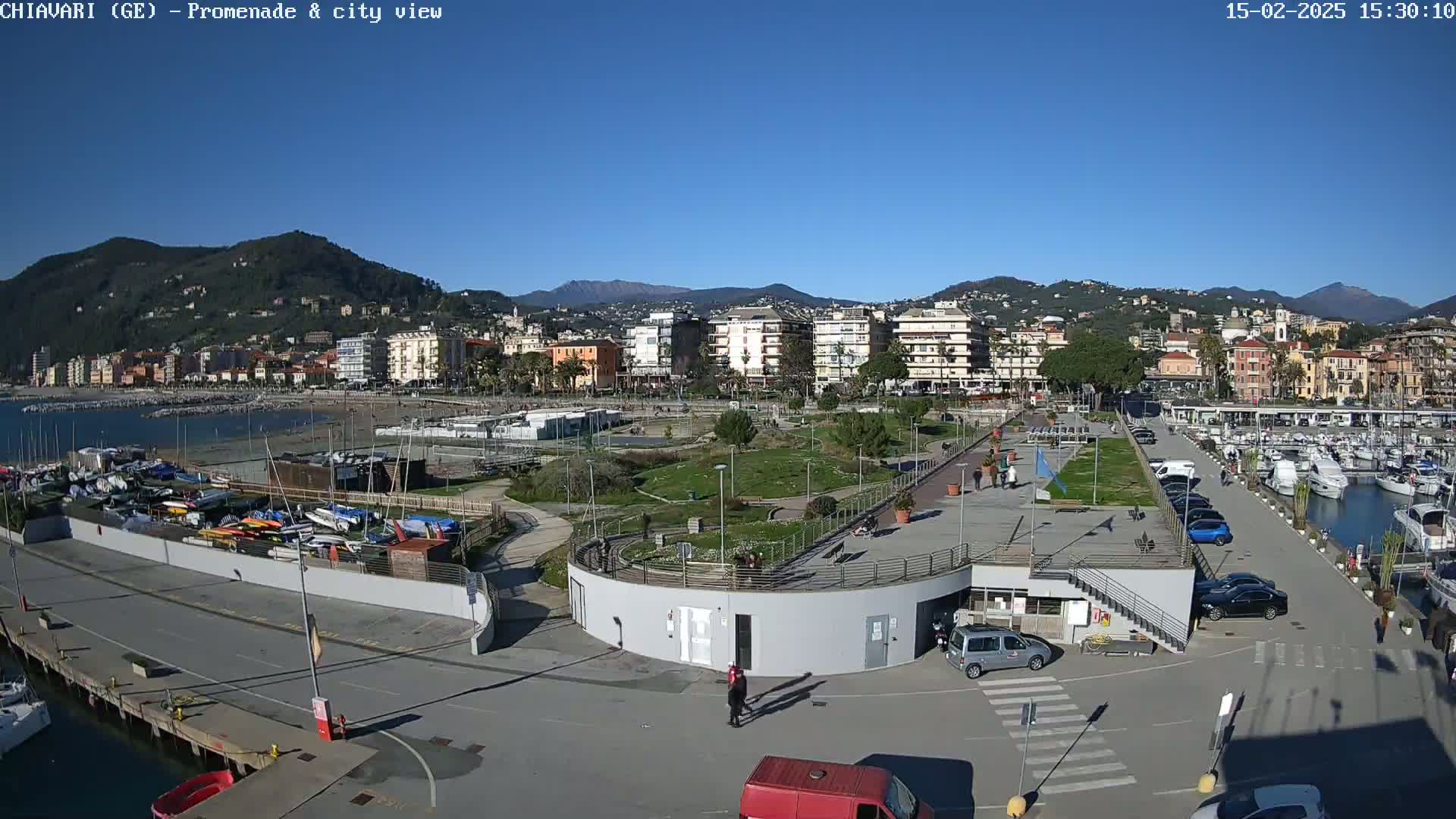 A seaside town with a marina, park, and residential buildings is seen on a clear, sunny day.