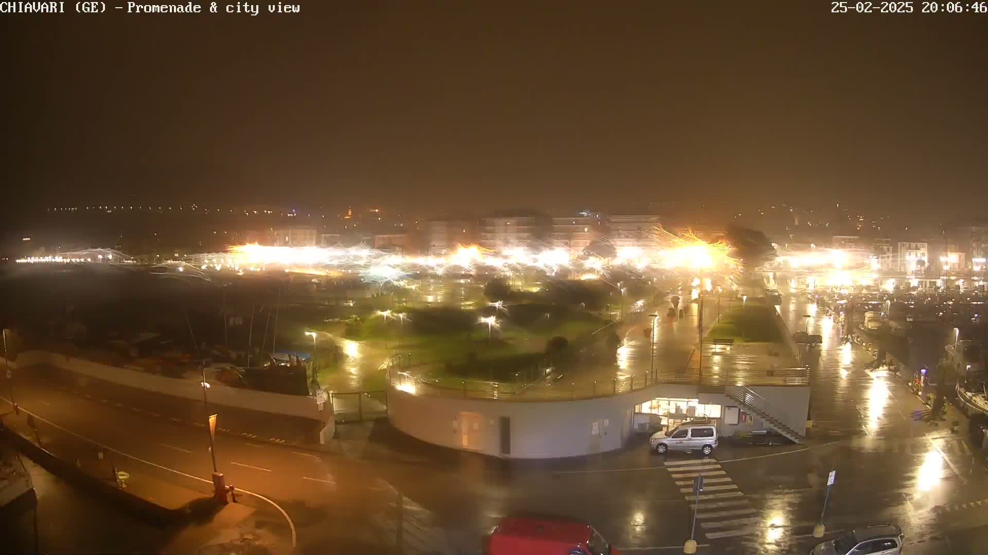 A nighttime, rain-soaked waterfront promenade and city area are shown with bright lights and fireworks displays in the background.