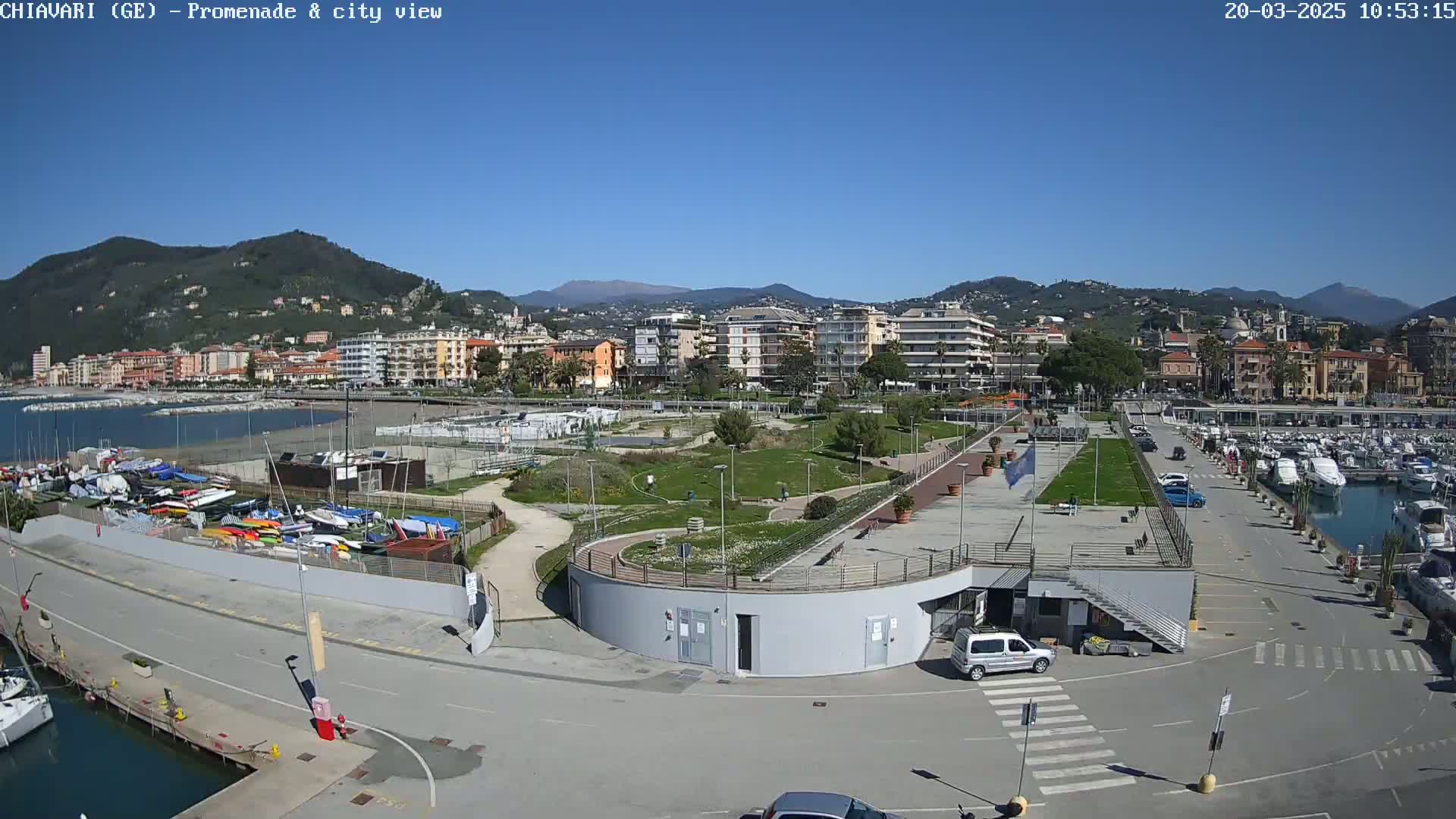 A seaside town with a marina, a promenade, and a park is shown on a sunny day.