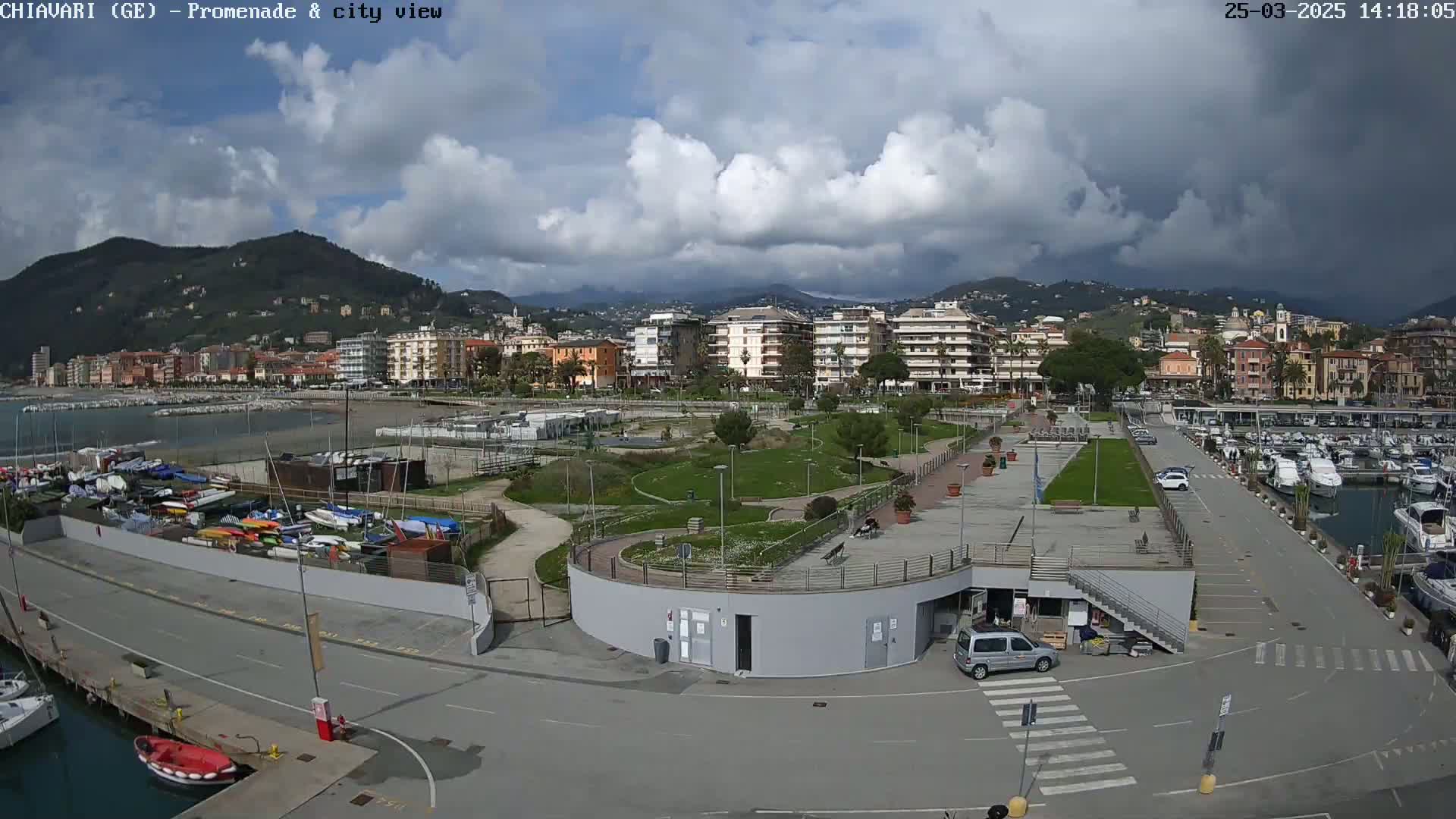 A coastal town with a marina, park, and buildings is visible under a partly cloudy sky.