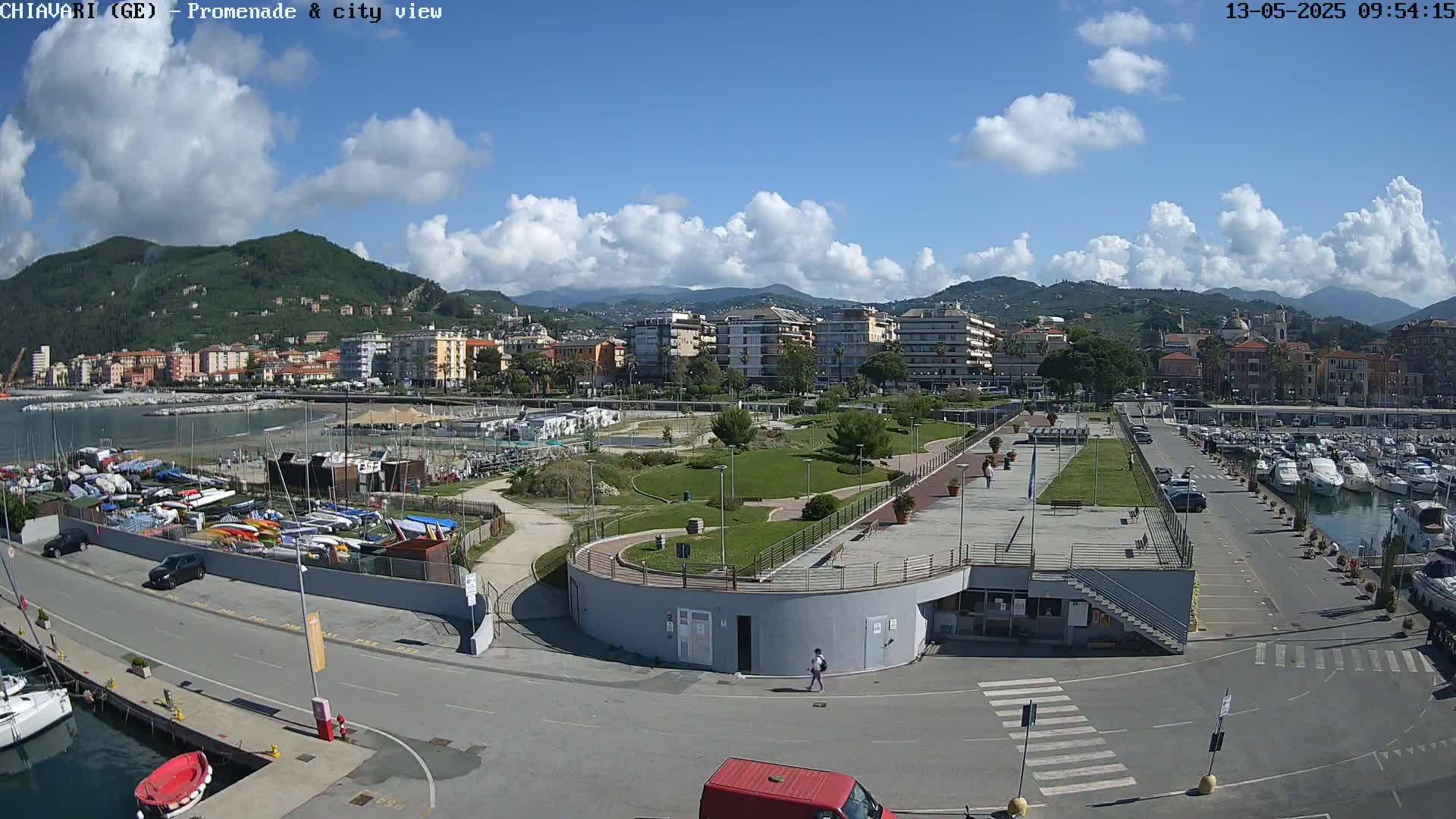 A seaside town with a marina, park, and residential buildings under a partly cloudy sky.