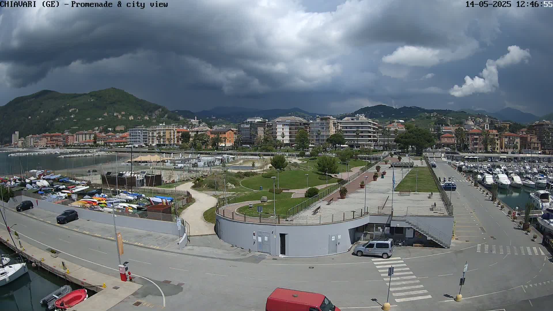 A coastal city with a marina and a promenade is shown under a partly cloudy sky.