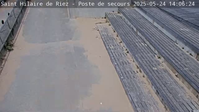 A high-angle view shows a long set of gray concrete steps and a paved area, with light-colored dust or sand scattered around.