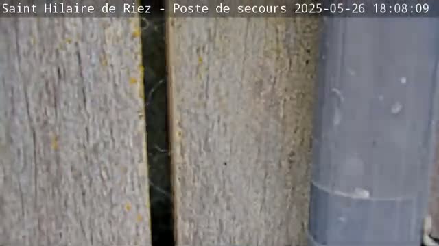 A close-up shows two weathered, gray wooden planks and a section of a gray pipe.