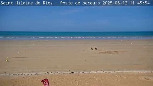 A wide sandy beach stretches to a calm, turquoise ocean under a clear blue sky.