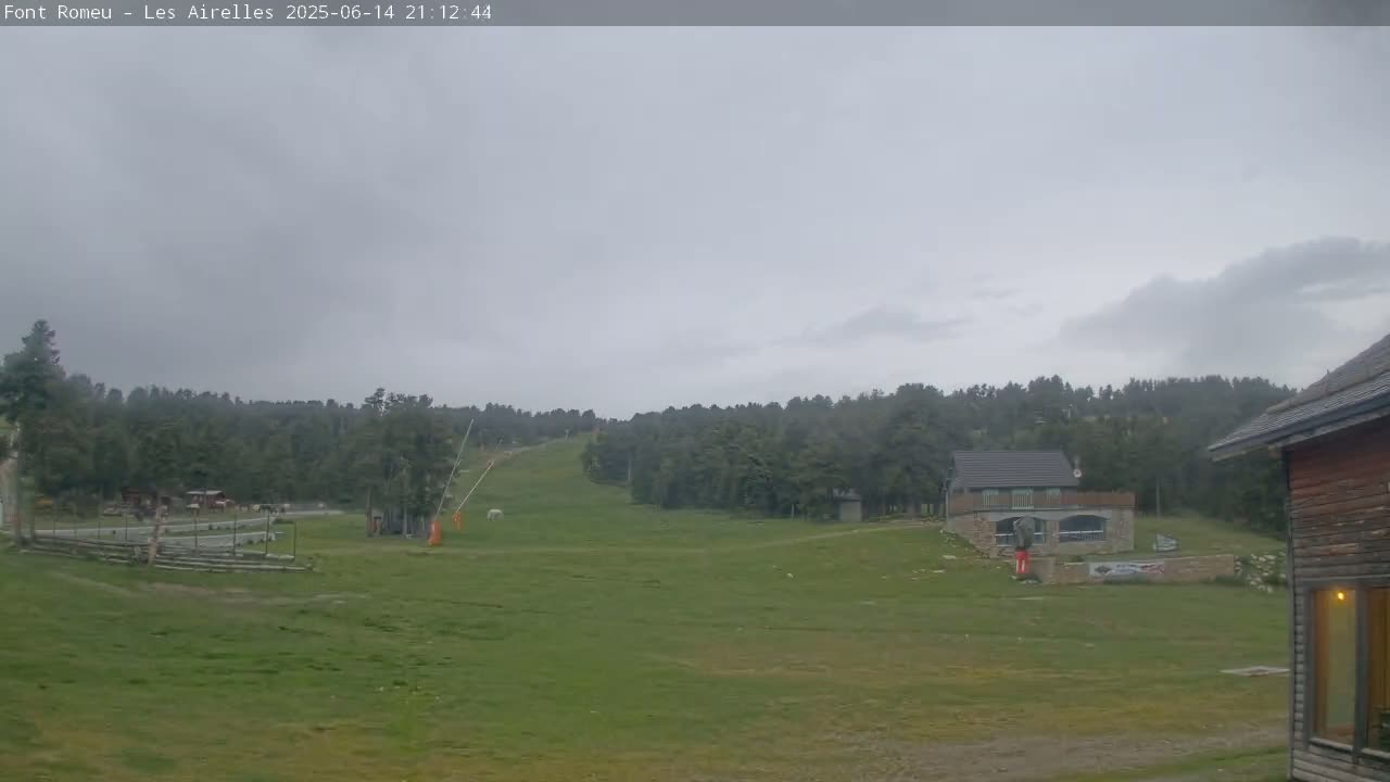 A grassy hillside with a ski lift and a few buildings is visible under a partly cloudy sky.