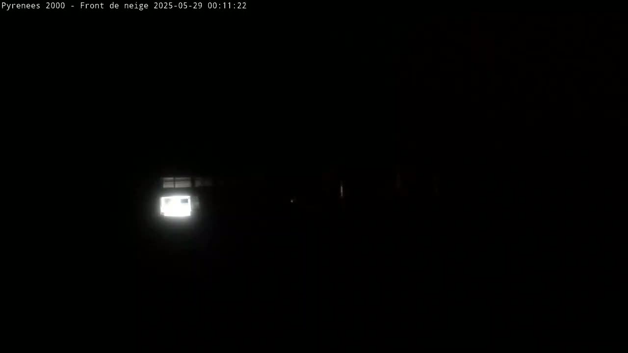 A dimly lit, dark scene at night shows a brightly lit window of a building in the distance.
