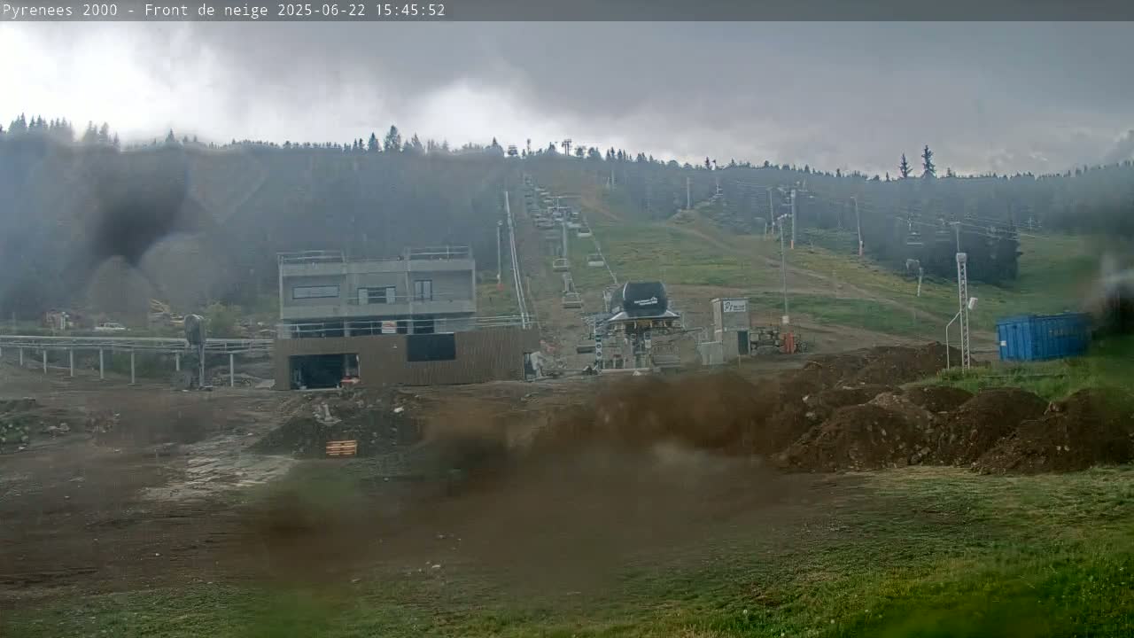 A ski lift ascends a hillside under an overcast sky, with construction visible at the base of the hill.