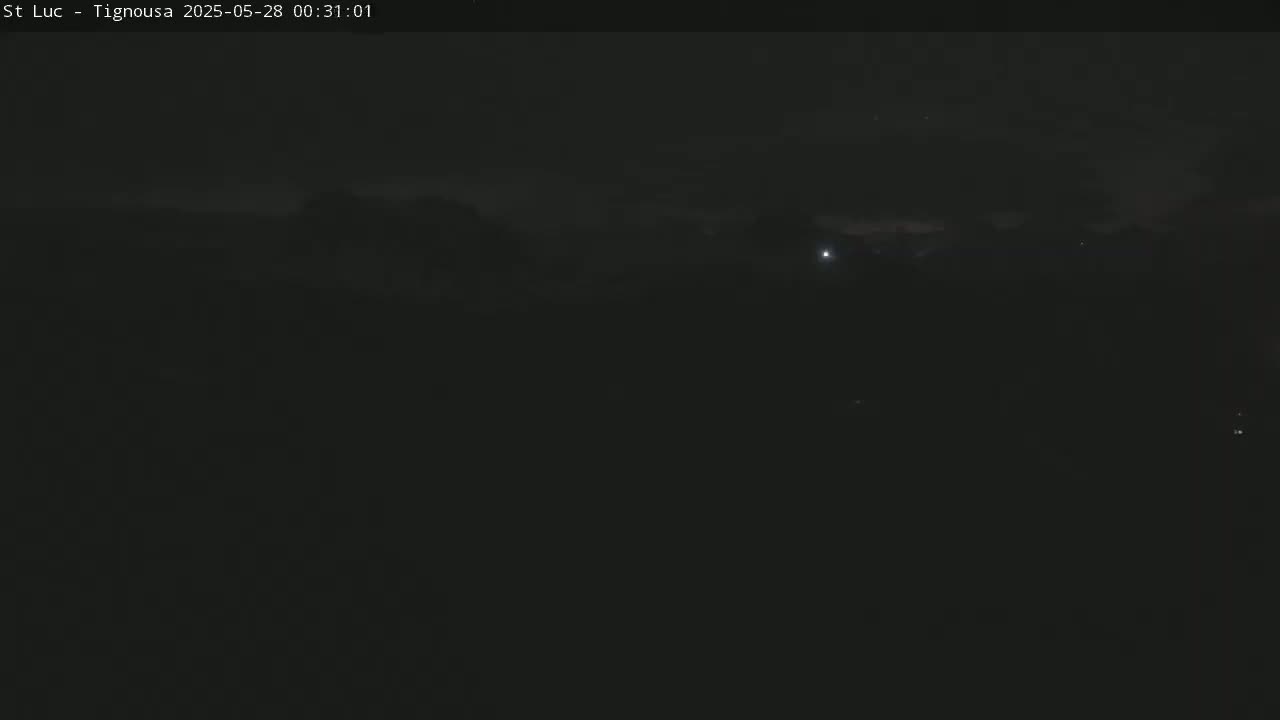 A dark, nighttime outdoor scene shows a mostly clear sky with a few faint lights in the distance.