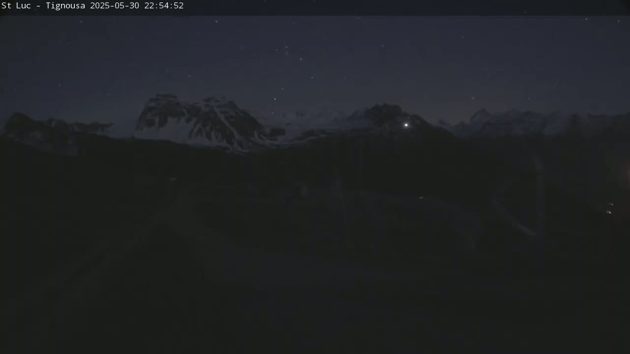 Snow-capped mountains are visible under a dark, clear night sky with a few stars.