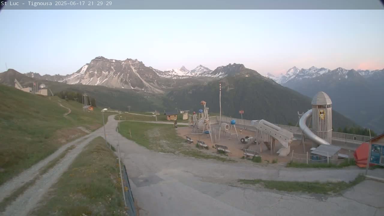A playground sits in the foreground of a mountain vista under a clear, twilight sky.