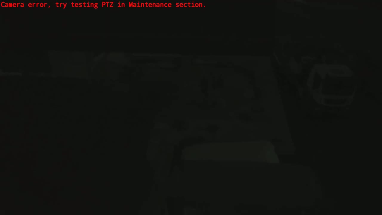 A dark, blurry image shows indistinct shapes and objects in low-light conditions.