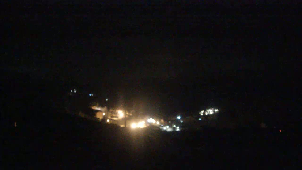A blurry nighttime view of a distant town's lights scattered across a dark landscape.