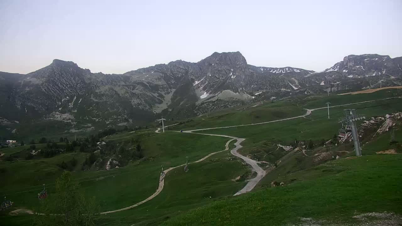 A mountain village nestled in a valley, with green hills and a partly cloudy sky.