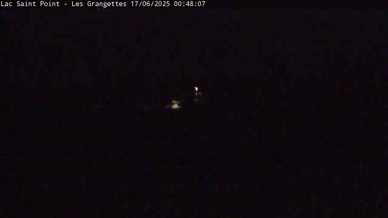 A dark, nighttime scene shows faint lights in the distance.