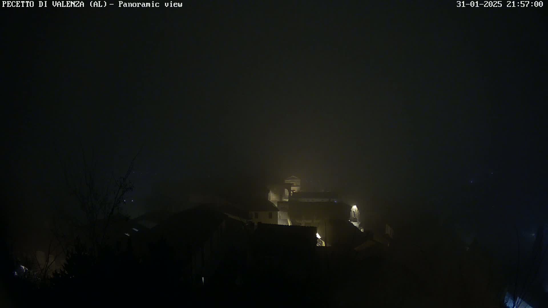 A foggy night scene shows dimly lit buildings in a small town.
