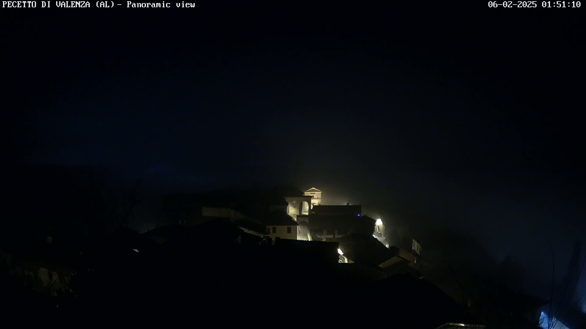 A foggy night scene shows a small village with dimly lit buildings.