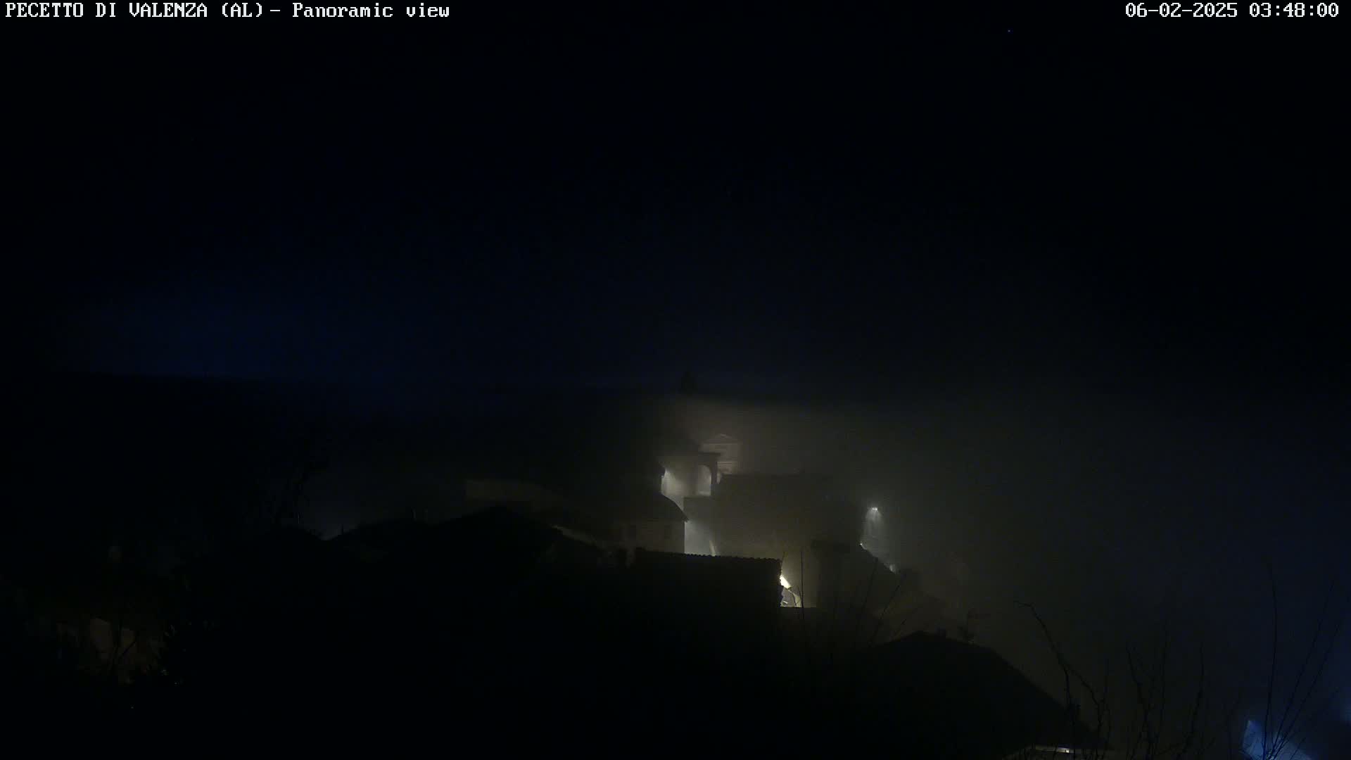 A foggy night scene shows dimly lit buildings shrouded in mist.