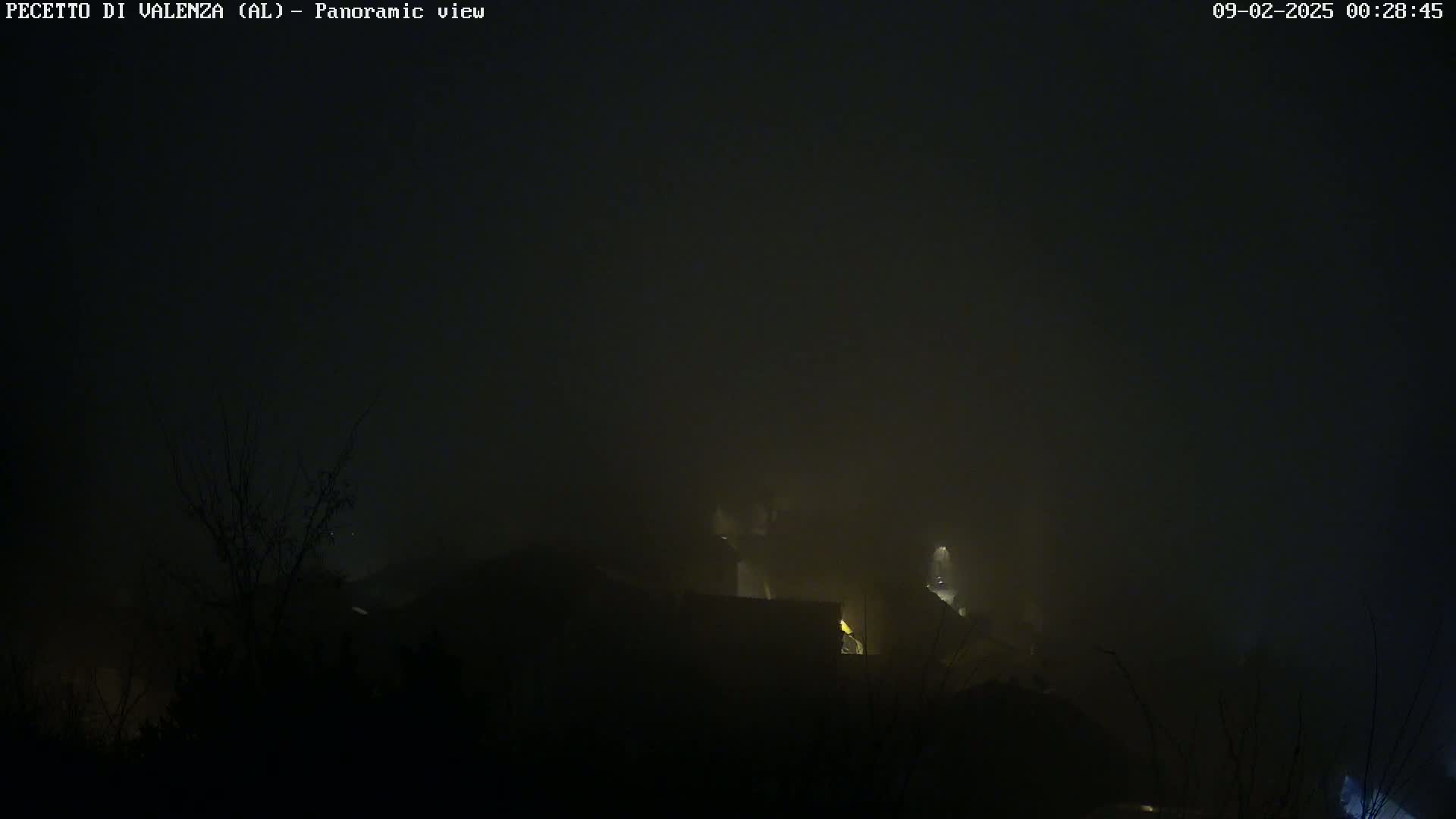 A foggy night scene shows dimly lit buildings nestled in the hills.