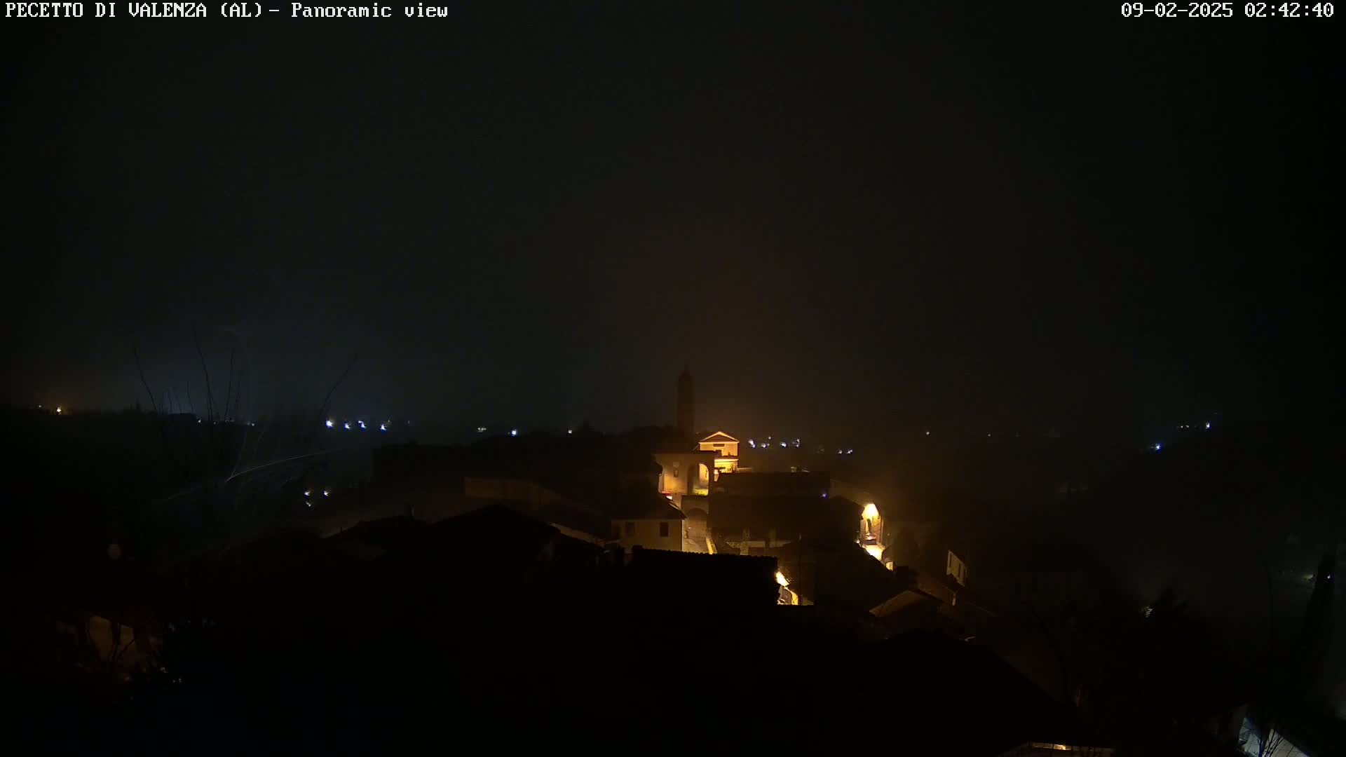 A nighttime, foggy view of a small village with dimly lit buildings.