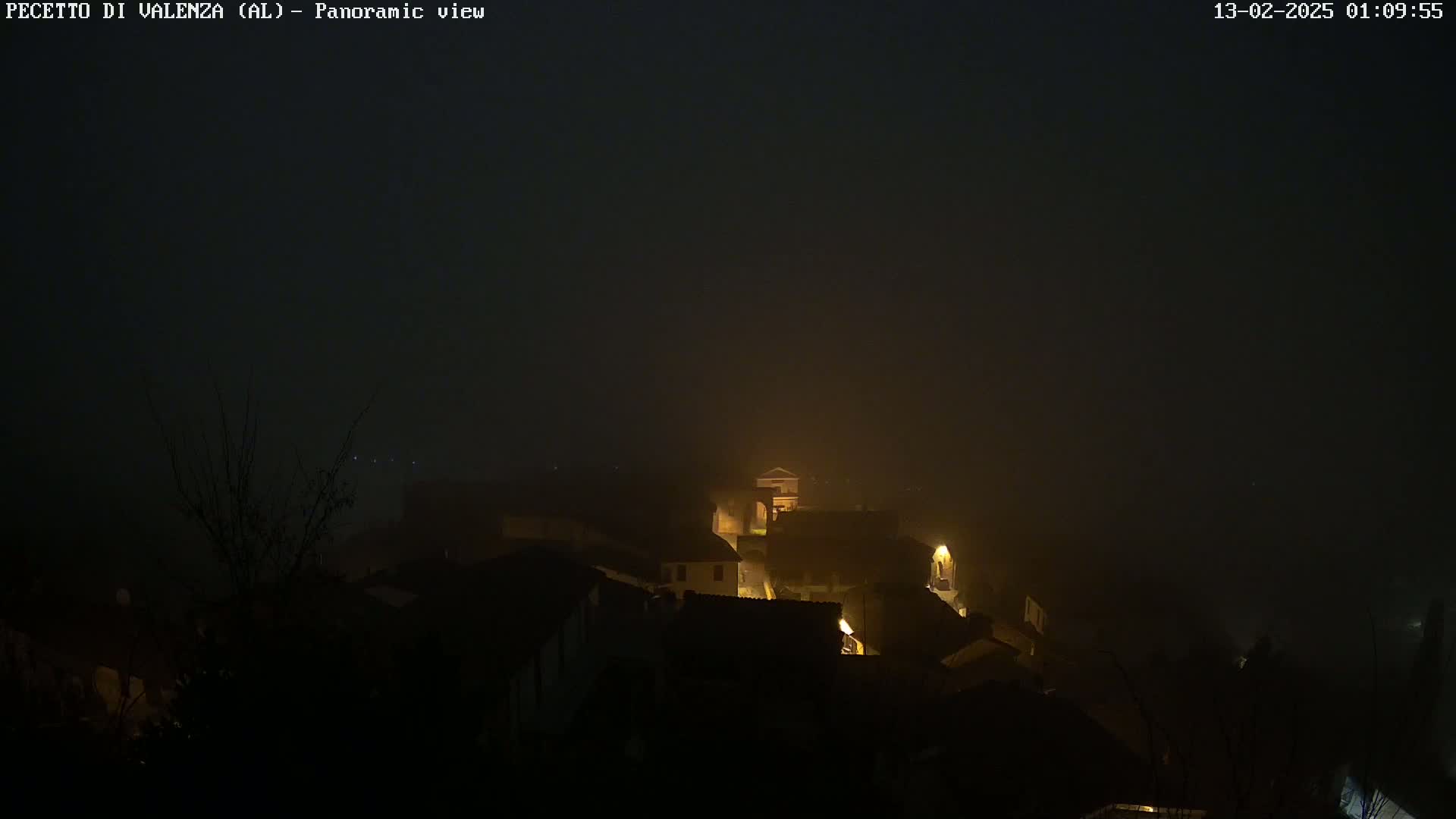 A foggy night scene shows a small village with dimly lit buildings.