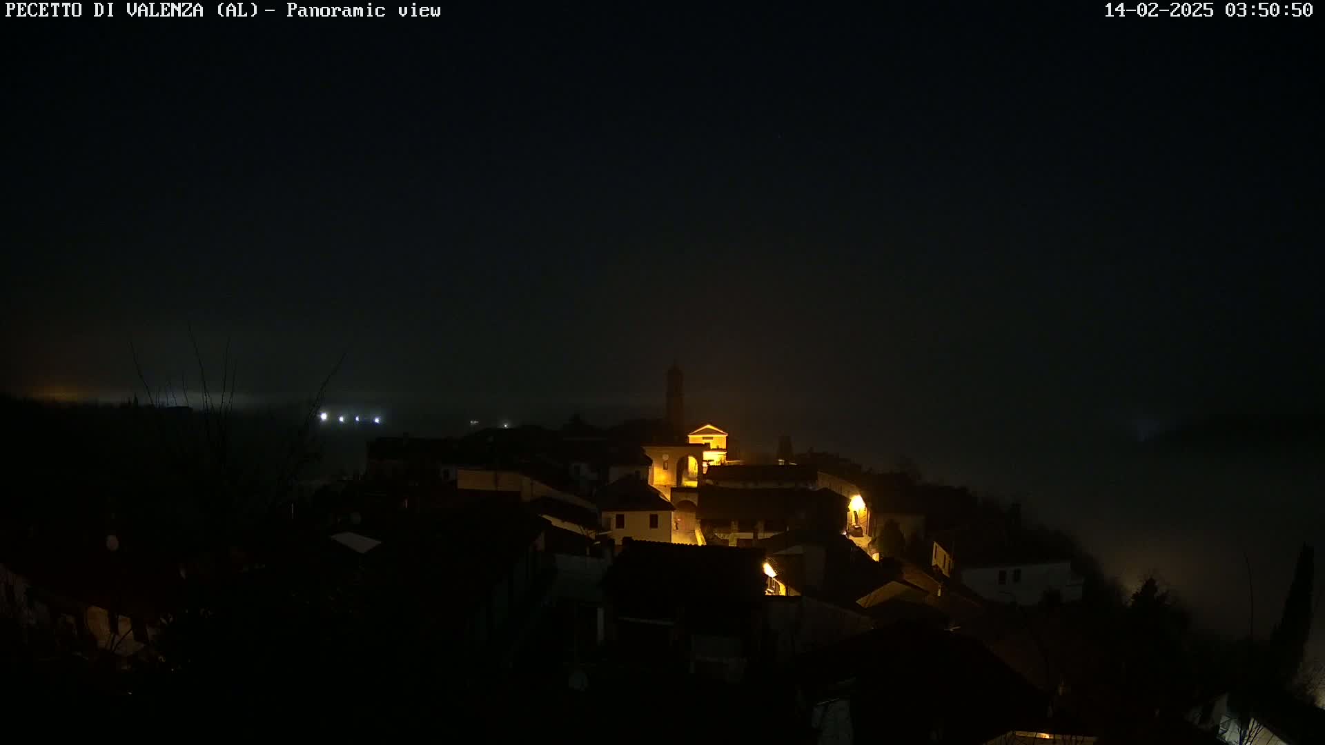 A small, dimly lit town is shrouded in fog at night.