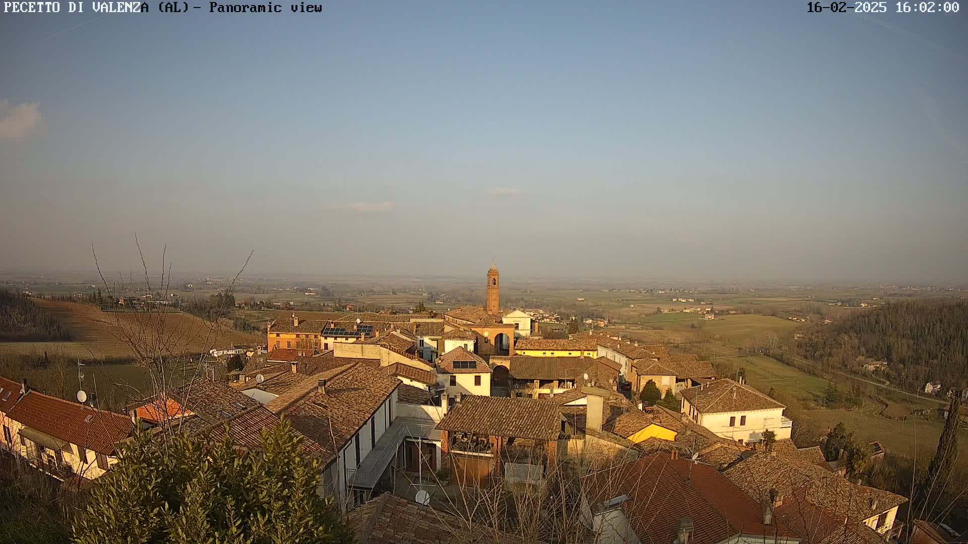 A panoramic view of a village nestled in a valley, under a clear, light-blue sky.