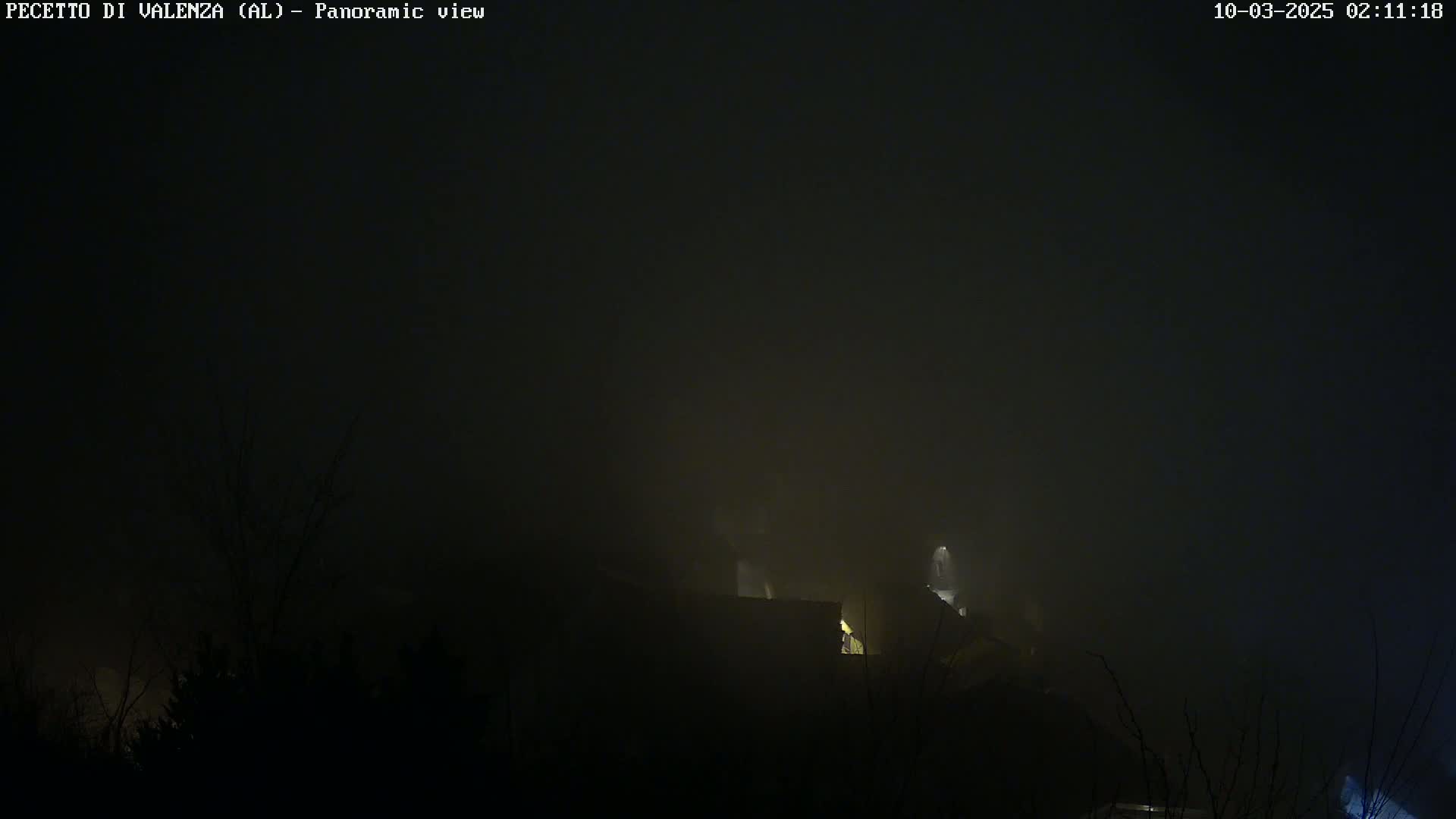 A dimly lit building is barely visible through a thick fog at night.