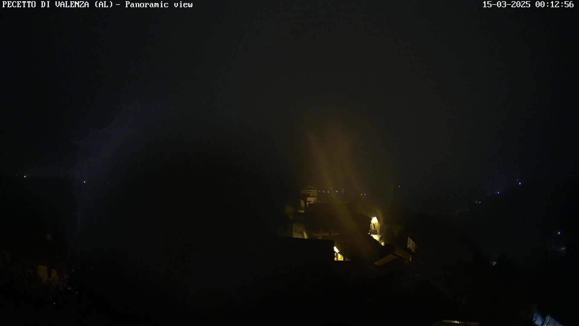 A nighttime, foggy scene shows a small village with dimly lit buildings, and lightning strikes in the distance.