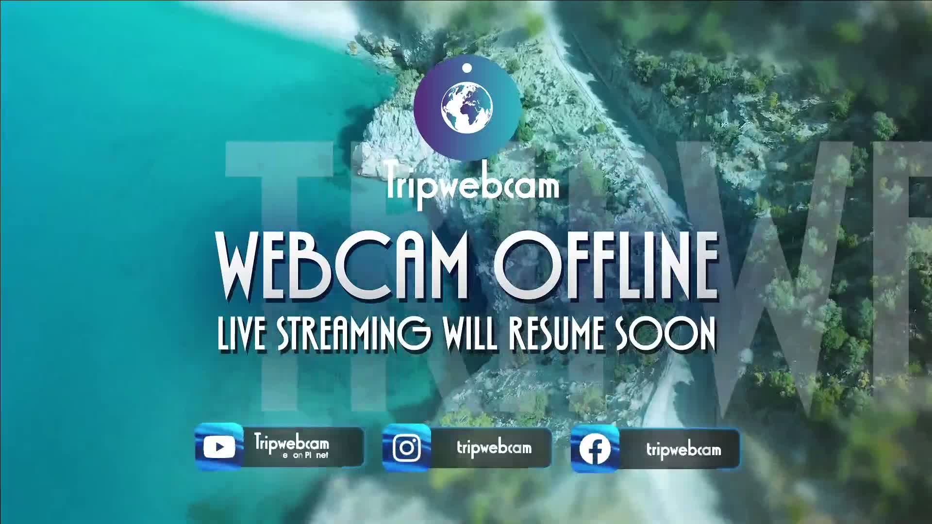An aerial view of a rocky coastline meeting turquoise water, overlaid with a "webcam offline" message.