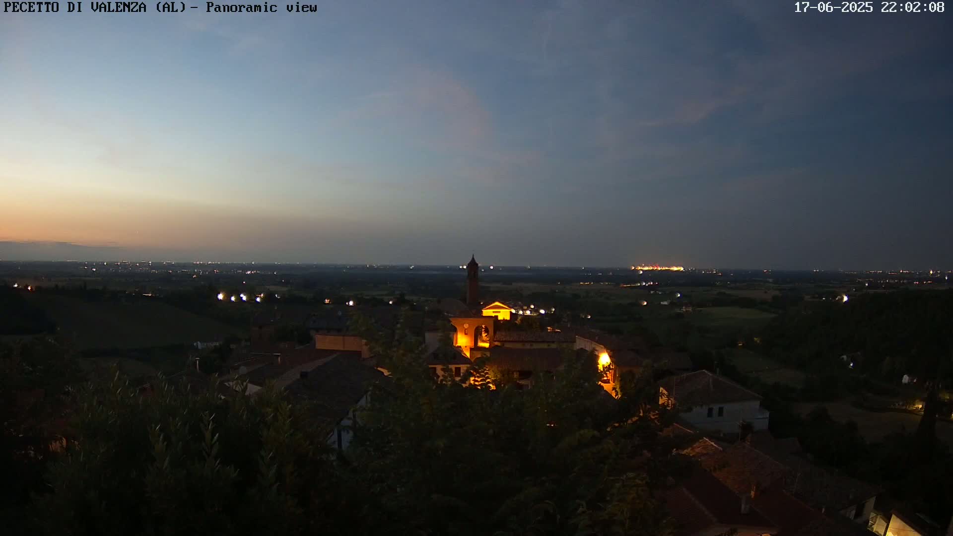 A small, illuminated town nestled in a dark green landscape under a twilight sky.
