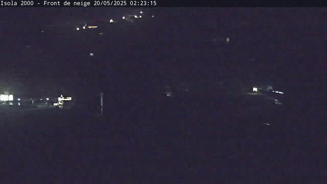 A dark, nighttime scene shows faint lights in the distance, possibly indicating vehicles or buildings.