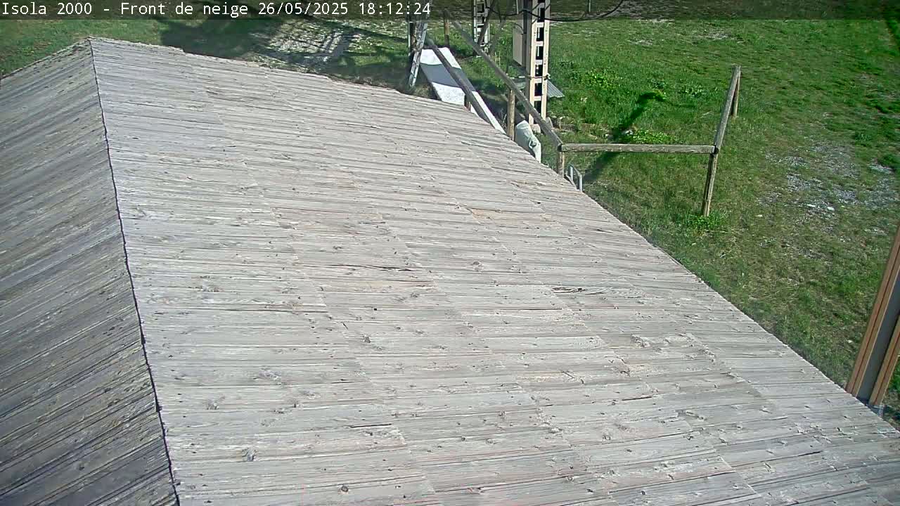 A sloped wooden deck extends from a building into a grassy area under sunny conditions.