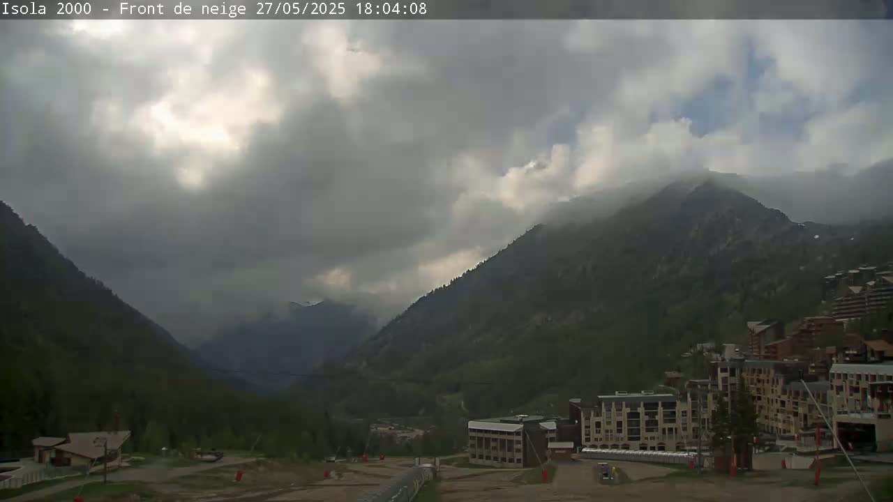 A cloudy, overcast day reveals a mountain valley with buildings and ski lifts in the foreground.