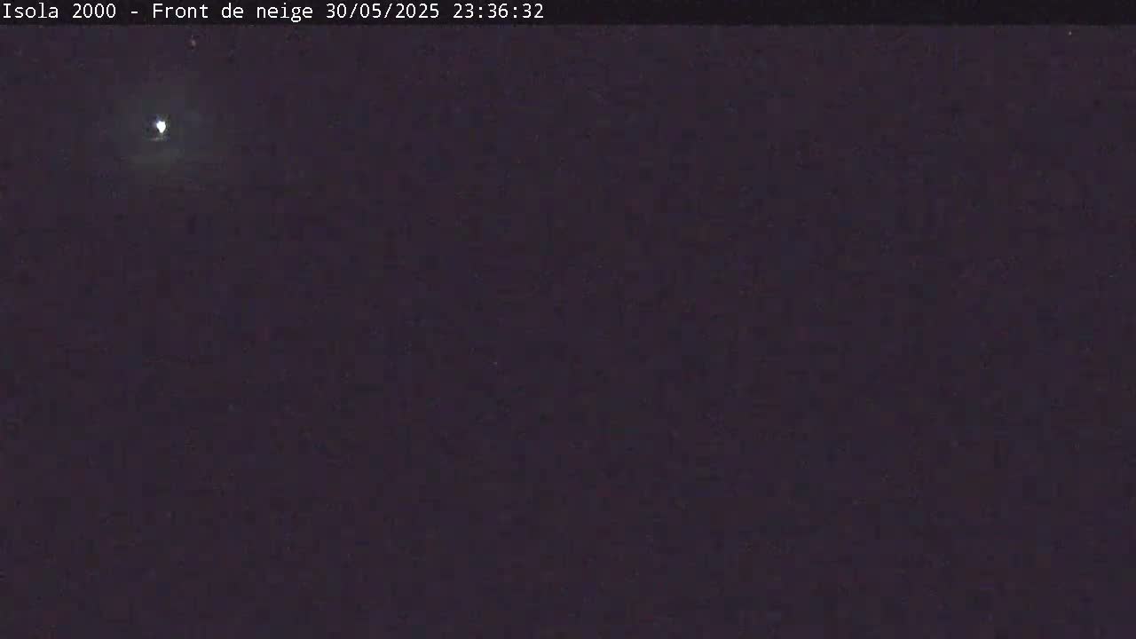 A nighttime, dark image shows a bright moon in a mostly clear sky.