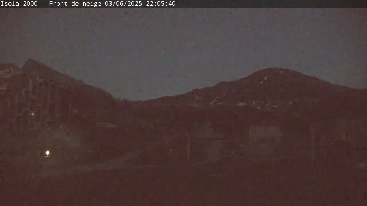 A nighttime, dark view of mountains and buildings under a dusky sky.